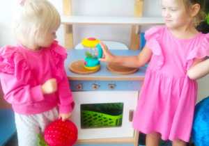 Dziewczynki bawią się w kąciku kuchennym.