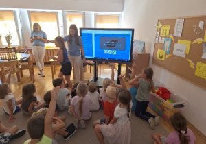 Dzieci grają w gre na ekranie multimedialnym.