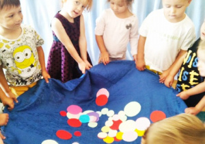 Dzieci podrzucają kolorowe kropki.