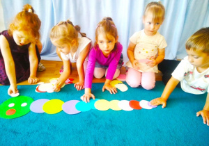 Dziewczynki układają gąsienicę z kolorowych kropek.