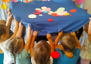 Dzieci podrzucają kolorowe kropki.
