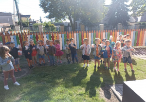 Dzieci w rękawiczkach gotowe do sprzątania terenu w ogrodzie przedszkolnym.