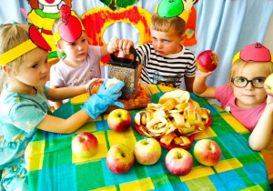 Dzieci ścierają jabłka na tarce.