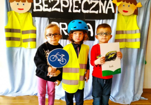 Dzieci pokazują , jak prawidłowo należy się ubrać na wycieczkę rowerową.