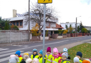 Dzieci stoją przy znaku, który informuje nas o przejściu dla pieszych.