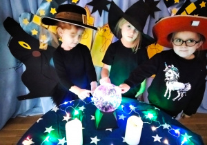 Zosia M, Helenka i Julia wypowiadają czarodziejskie zaklęcie przy pomocy magicznej kuli.