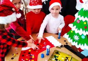 Dzieci wyklejają świąteczną skarpetę.