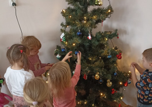 Dzieci ubierają świąteczne drzewko.