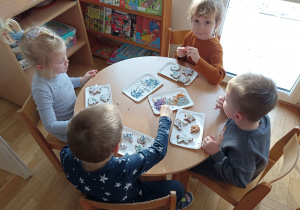 Dzieci przy czwartym stoliku dekorują upieczone pierniczki.