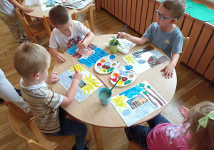 Dzieci przy pierwszym stoliku wykonują prace plastyczne.