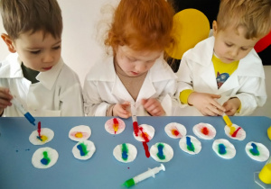 Dzieci napełniają strzykawki zabarwioną wodą i wyciskają na waciki kosmetyczne