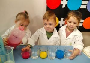 Dzieci zabarwiają wodę na kolor żółty, czerwony i niebieski za pomocą farb