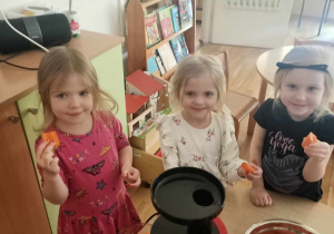 Ania, Zoja i Hania K. pokazują marchewki, które wrzucą do sokowirówki.