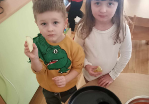 Szymon i Hania Sz. pokazują jabłka, które wrzucą do sokowirówki.