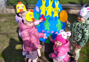 Dzieci przyklejają ozdoby na jajko.