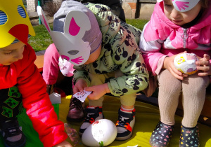 Dzieci naklejkami ozdabiają jajka ze styropianu.