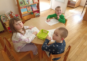 Dzieci przy drugim stoliku kolorują obrazki o tematyce wielkanocnej.