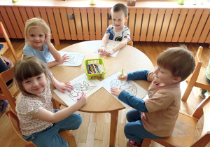 Dzieci przy czwartym stoliku kolorują obrazki o tematyce wielkanocnej.