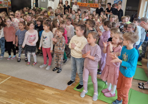 Dzieci z zaciekawieniem słuchają śpiewanej piosenki.