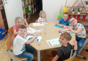 Dzieci przy pierwszym stoliku wykonują pracę plastyczną.