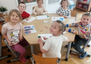 Przedszkolaki przy drugim stoliku wykonują pracę plastyczną.