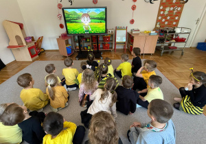 Przedszkolaki oglądają film edukacyjny o pszczołach.