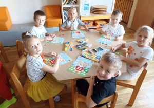 Przedszkolaki przy drugim stoliku wykonują pracę plastyczną „Miś z kropek”.
