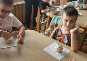 Dzieci przy trzecim stoliku dekorują babeczki.