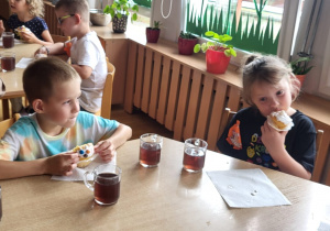Przedszkolaki przy czwartym stoliku jedzą słodki podwieczorek.