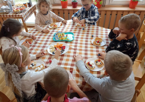 Przedszkolaki przy trzecim stoliku przygotowują gofry.