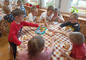 Dzieci przy czwartym stoliku przygotowują gofry.