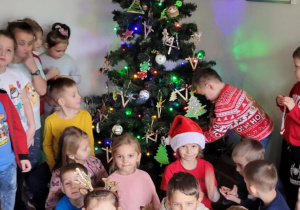 Dzieci ozdabiają choinkę w holu przedszkola.