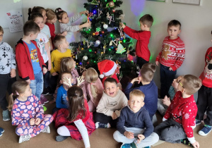 Dzieci ozdabiają choinkę w holu przedszkola.