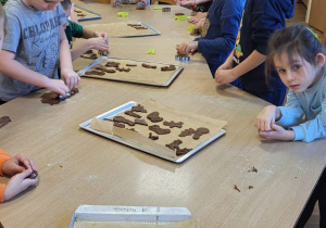Dzieci wykrawają pierniczki i układają je na blaszkach.