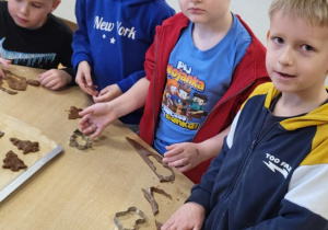 Dzieci wykrawają pierniczki i układają je na blaszkach.