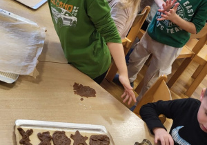 Dzieci wykrawają pierniczki i układają je na blaszkach.