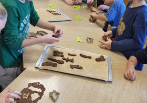 Dzieci wykrawają pierniczki i układają je na blaszkach.