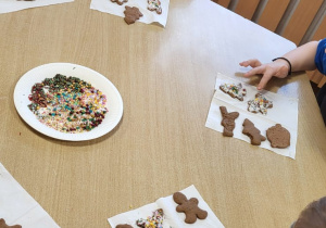 Przedszkolaki dekorują upieczone pierniczki.