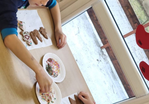 Przedszkolaki dekorują upieczone pierniczki.