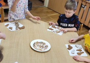 Przedszkolaki dekorują upieczone pierniczki.