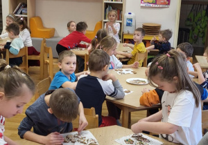 Przedszkolaki dekorują upieczone pierniczki.