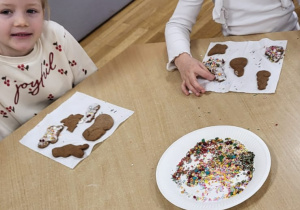 Przedszkolaki dekorują upieczone pierniczki.