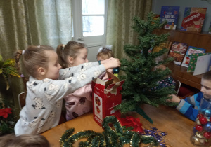 Przedszkolaki ubierają choinki.