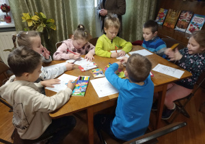 Przedszkolaki kolorują zimowe i świąteczne obrazki.