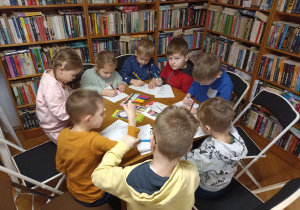 Przedszkolaki kolorują zimowe i świąteczne obrazki.