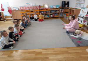 Pani instruktorka opowiada przedszkolakom o zasadach prawidłowej opieki nad psem.