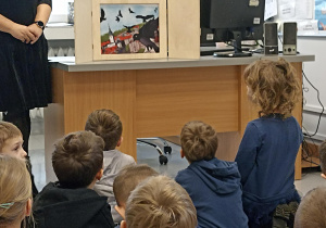 Przedszkolaki słuchają treści bajki z wykorzystaniem teatrzyku kamishibai.