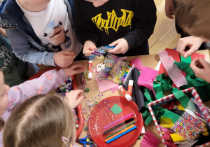 Dzieci wybierają materiały do wykonania masek karnawałowych.