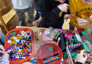 Dzieci wybierają materiały do wykonania masek karnawałowych.