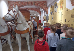 Grupa pomarańczowa zwiedza wnętrza budynku.